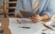 Image of someone paying bills sitting at a table.