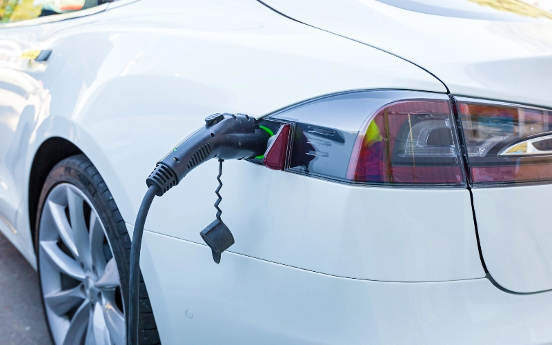 Image of a white electric vehicle plugged in and charging.